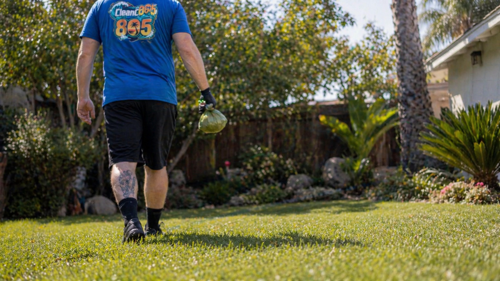Clean Club 805 technician walking across a tidy backyard lawn after a dog waste pickup